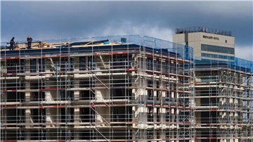 Arbeiter stehen auf dem Dach eines Rohbaus. Der Bundesverband deutscher Wohnungs- und Immobilienunternehmen benötigt mehr Geld für den klimagerechten Neubau.