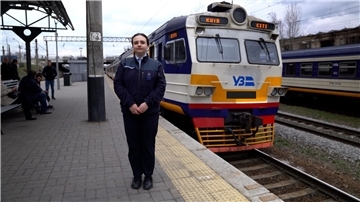 Assistenz-Zugführerin Viktoria Kikot vor dem Zug der Kiewer S-Bahn in einer Szene aus „Re: Die Eisenbahnladys der Ukraine - Wie sie den Schienenverkehr am Laufen halten“.