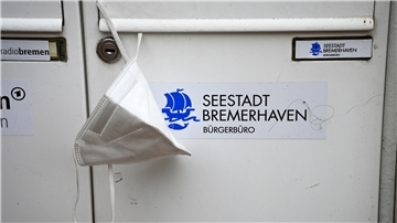 Eine FFP2-Maske hängt am Eingang zum Bürgerbüro Mitte in Bremerhaven. 