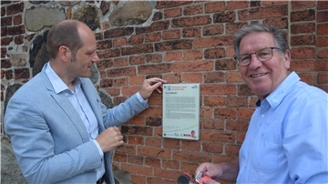 Auch an der Marienkirche in Geestemünde wurde eine Hinweistafel am denkmalgeschützten Gotteshaus montiert. Im Bild Pastor Lars C. Langhorst (links) und Standortmanager Thomas Ventzke.