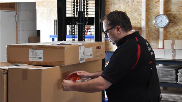 Eine ganz besondere Firma in Dorum: Hier werden Kino-Träume wahr (Video) Ein Mann klebt einen Versandsticker auf ein Paket.