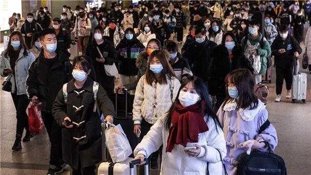  Passagiere kommen am Bahnhof Hankou an und tragen Mund-Nasen-Schutz. 