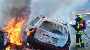 Ein brennendes Auto wird von einem Feuerwehrmann gelöscht