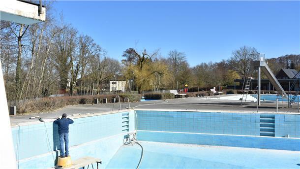 Saisonvorbereitung im Waldbad Sittensen: Neue Leitung, alte Technik Ein Maurer steht auf einem Gerüst im tiefen Sprungbecken und bessert Fliesen am Beckenrand aus.