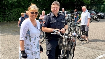 Ein Polizist codiert ein Fahrrad, die Besitzerin steht daneben.