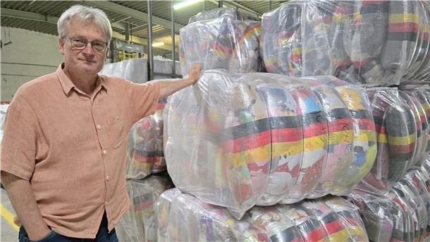 Ein Mann neben gepressten Ballen mit Stofftieren