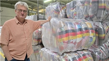 Ein Mann neben gepressten Ballen mit Stofftieren