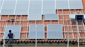 Ein Arbeiter montiert Solarmodule auf einem Dach
