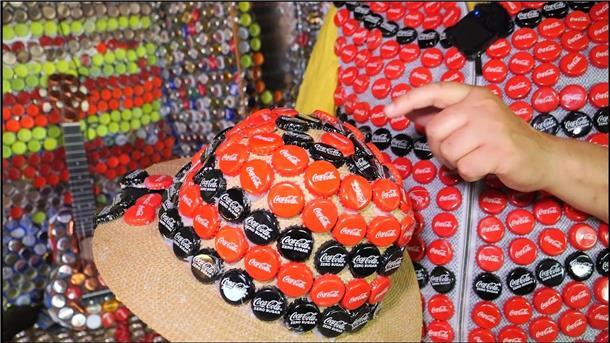 Auf dem Hut kleben die Deckel von vielen leeren Cola-Flaschen.