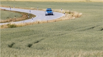 Ein Polizeiwagen fährt auf einer Straße durch Landwirtschaftliche Nutzfläche.