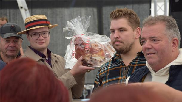 Der Sammler Marijano Weimar hält den Schweinskopf in der Hand und geht durch das Festzelt.