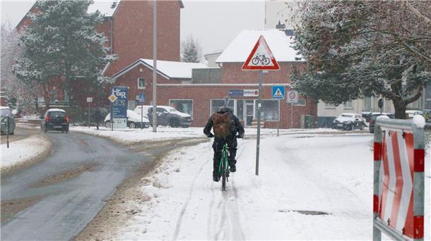 Auf der Cuxhavener Poststraße ist ein Radfahrer auf dem bereits wieder mit Schnee bedeckten Radfahrstreifen unterwegs .