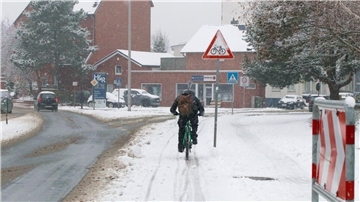 Auf der Cuxhavener Poststraße ist ein Radfahrer auf dem bereits wieder mit Schnee bedeckten Radfahrstreifen unterwegs .