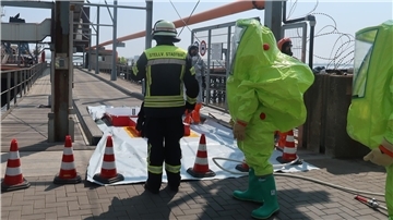 Auf der Glencore-Pier, auf der die Leckage entstanden ist, sind Helfer in spezieller Schutzkleidung im Einsatz.