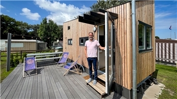 Mann steht vor der Tür eines Tiny-Houses.