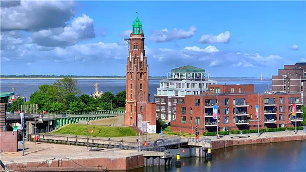 Blick auf einen Leuchtturm mit einer Fassade aus rotem Backstein und einer grünen Spitze.