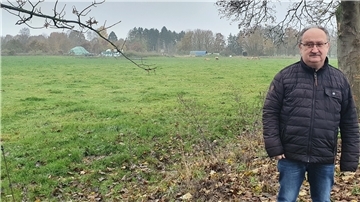 Ralf Wolter steht vor einem noch unbebauten Grundstück.