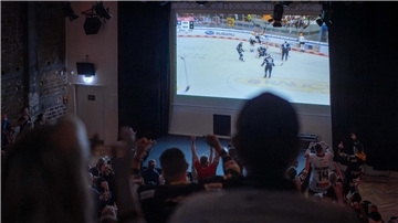 Fans fiebern vor einer Leinwand bei einem Spiel mit. Die Fischtown Pinguins kämpfen in den Playoffs gegen Köln um den Halbfinaleinzug.