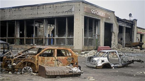 Ausgebrannte Autos stehen vor einem Autohaus, das durch russischen Beschuss in Isjum zerstört wurde.