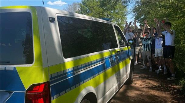Ein Polizeibus und davor jubelnde junge Menschen.