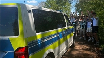 Ein Polizeibus und davor jubelnde junge Menschen.
