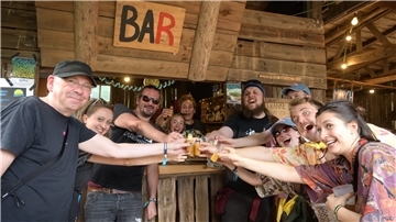 Mehrere Menschen feiern ausgelassen beim Festival "Frida rockt". Hier stoßen sie gemeinsam vor der Bar an.