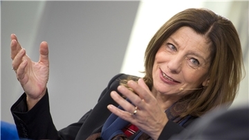 Eine Frau spricht lächelnd und gestikuliert dabei mit den Händen. 