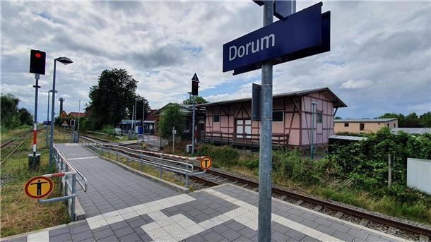 Eisenbahngleise und ein Gebäude im Hintergrund. Im Bild zu sehen ist der Bahnhof Dorum.  