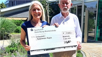 Barbara Treffert übergibt Ludwig Most einen symbolischen Scheck. Aus dem Verkauf von Fotos, die Andreas Dittmer aufgenommen hatte, fließen 1.000 Euro an das Hospiz in Bremervörde.