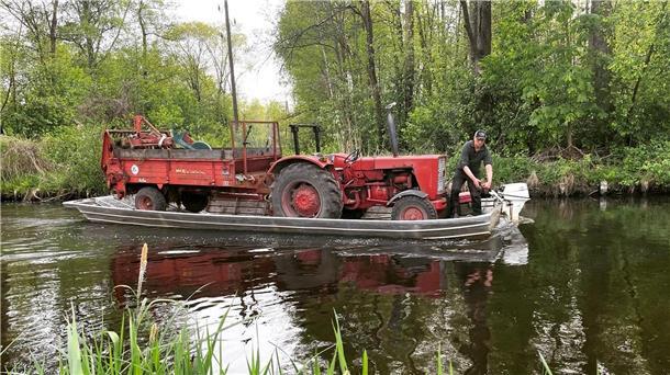 Bauer Sebastian Kilka aus dem Spreewald fährt den Miststreuer auf seinem Kahn über ein Fließ.