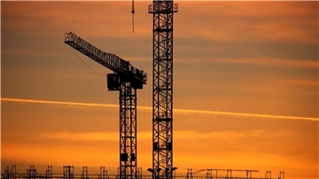 Baukräne einer Großbaustelle im Sonnenaufgang: Das Geschäftsklima verbesserte sich in allen betrachteten Wirtschaftsbereichen.