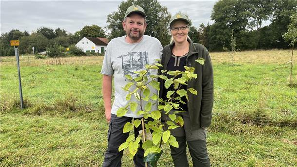 Ein Mann und eine Frau stehen vor einem kleinen Baum. 