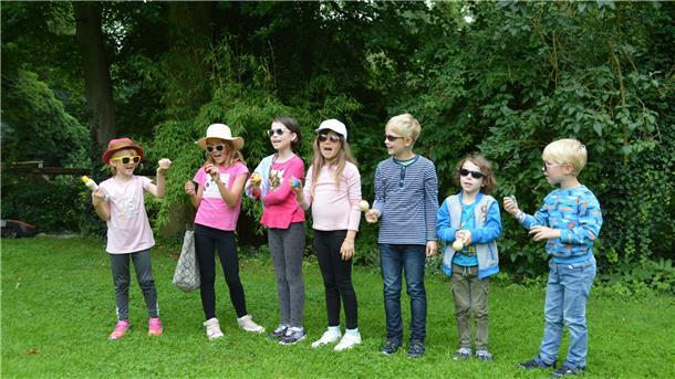 Sieben Kinder stehen auf einer Wiese.