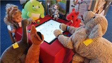 Kuscheltiere sind um einen Spieltisch versammelt
