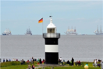 Ein Leuchtturm vor Segelschiffen
