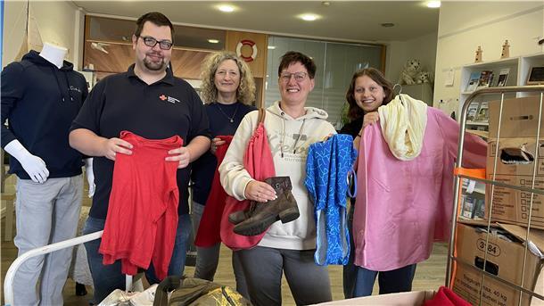 Ein Mann und drei Frauen halten Kleidung und Schuhe in den Händen