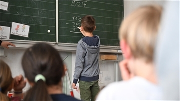 Ein Schüler steht an der Tafel einer Schulklasse.