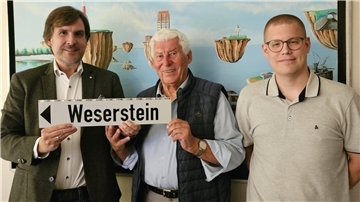 Drei Männer mit dem Schild „Weserstein"