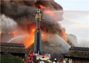 Feuerwehrleute kämpfen von einer Drehleiter aus gegen einen Großbrand