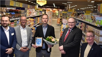 Fünf Männer stehen in einem neuen Supermarkt.
