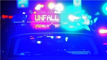 Ein Streifenwagen der Polizei steht mit Blaulicht an einer Unfallstelle.