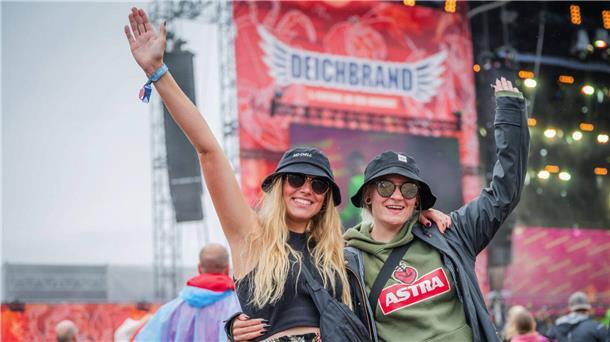 Party, Matsch und verrückte Outfits: Die besten Bilder vom Deichbrand 2023 Zwei Frauen posieren vor einer Deichbrand-Bühne.