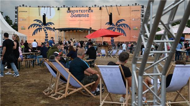 Eine Festivalfläche mit Bühne im Hintergrund. 