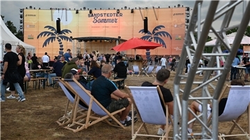 Eine Festivalfläche mit Bühne im Hintergrund. 