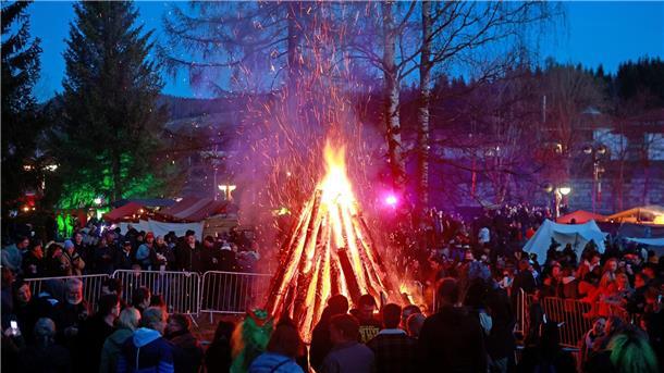 Besucher stehen auf dem Walpurgisfest in Schierke am Feuer.