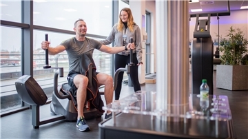 Neujahrsvorsätze für mehr Aktivität: Marie, Mitarbeiterin bei Ebene 2 Fitness in der Oberen Bürger, zeigt André Liekefeld die richtige Übungsweise am Gerät. 