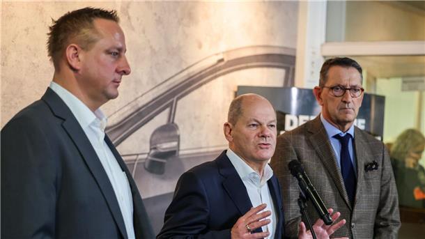 Förderspritze für Elektroautos? Scholz sieht Brüssel am Zug Betriebsratschef Benjamin Gruschka (l) neben Bundeskanzler Olaf Scholz (SPD) und Marcus Wassenberg (r), Geschäftsführer der Ford-Werke.