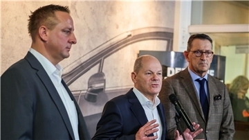 Betriebsratschef Benjamin Gruschka (l) neben Bundeskanzler Olaf Scholz (SPD) und Marcus Wassenberg (r), Geschäftsführer der Ford-Werke.