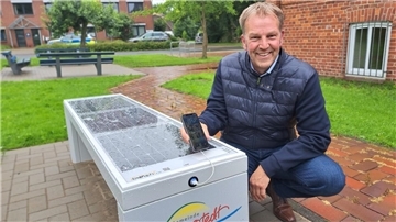  Beverstedts Bürgermeister Guido Dieckmann (parteils) lädt sein Smartphone an der neuen Smart-Solar-Bank am Jugendhaus auf. Die Solarzellen sind sicher unter Plexiglas in der Sitzfläche integriert. 
