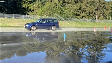 Schüler absolvieren Fahrsicherheitstraining Auto vor riesiger Pfütze